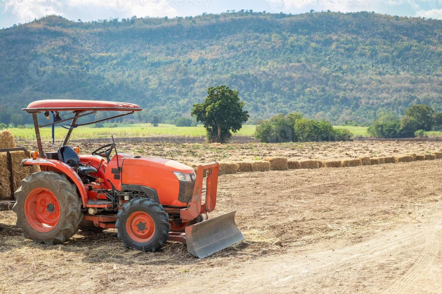 traktor i lantbruk fält med berg och blå himmel foto