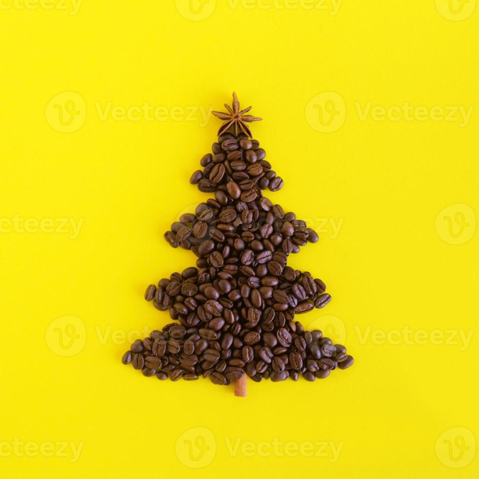 vinter- sammansättning med jul träd tillverkad förbi kaffe bönor och dekorerad anis stjärna och kanel pinne på en gul bakgrund, platt lägga. hälsning kort för ny år med kopia Plats. foto