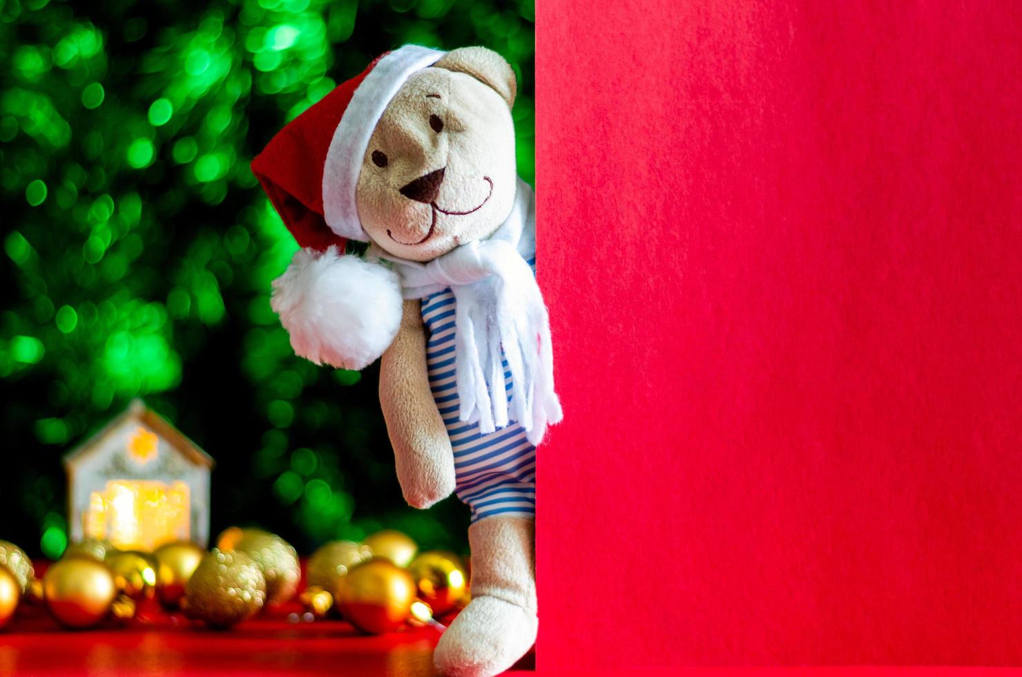 santa claus teddy Björn står bredvid tömma röd kort med färgrik ornament och jul träd bakgrund. foto