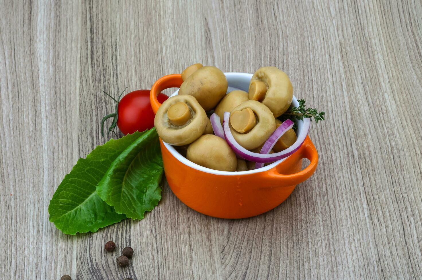 marinerad champignons i en skål på trä- bakgrund foto