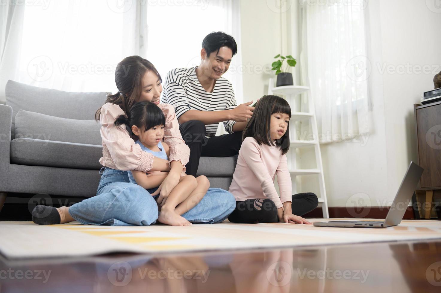 asiatisk familj med barn använder sig av bärbar dator dator på Hem foto