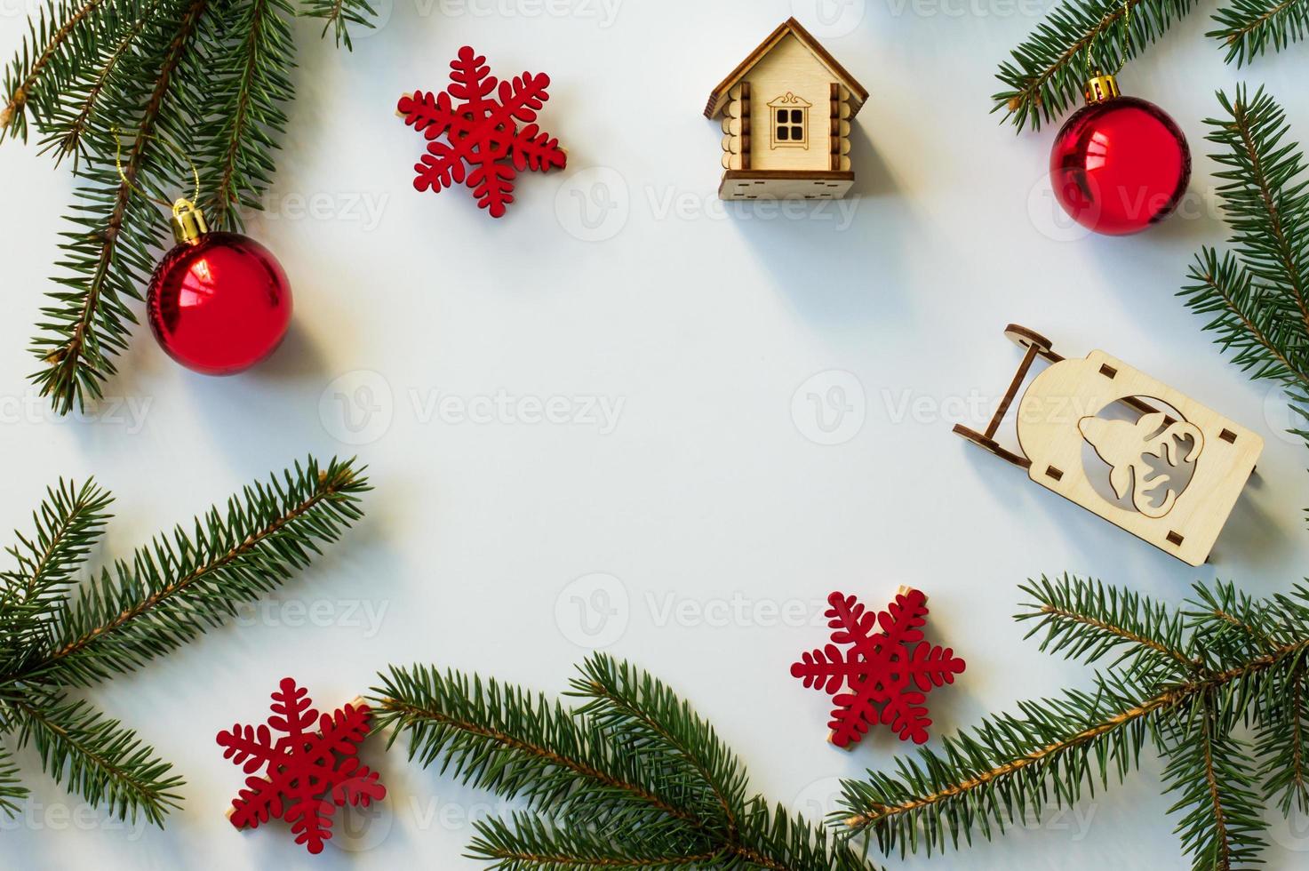 ny år eller jul bakgrund med gran grenar, röd bollar och snöflingor. trä- leksaker. platt layout. topp se. vit bakgrund. foto