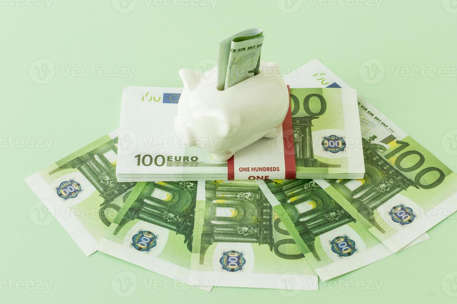 sedlar av 100 euro är lagd ut på en grön tabell med en packa av sedlar i en Bank klädsel och en nasse Bank på Det. lön, besparingar. foto