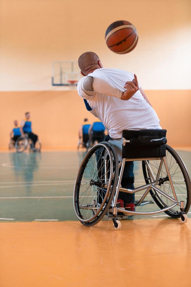 Inaktiverad krig veteraner blandad lopp och ålder basketboll lag i rullstolar spelar en Träning match i en sporter Gym hall. handikappade människor rehabilitering och inkludering begrepp foto