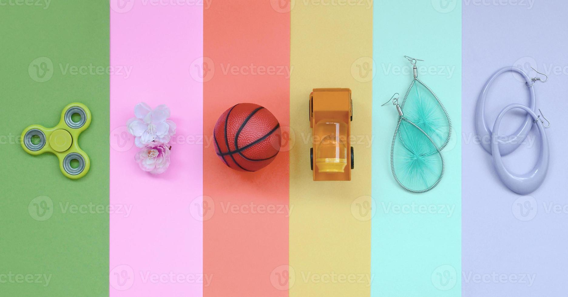 trendig pastell sammansättning med örhängen, solglasögon, dryck burk, basketboll boll, leksak lastbil, blomma och spinnare foto