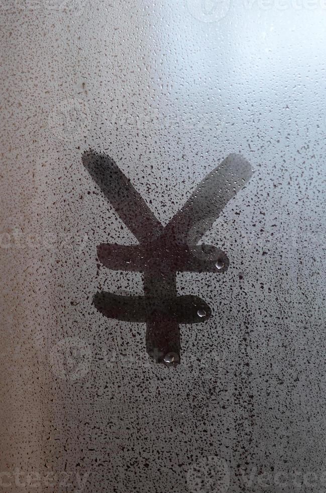 kinesisk yen symbol är skriven med en finger på de yta av de dimma glas foto
