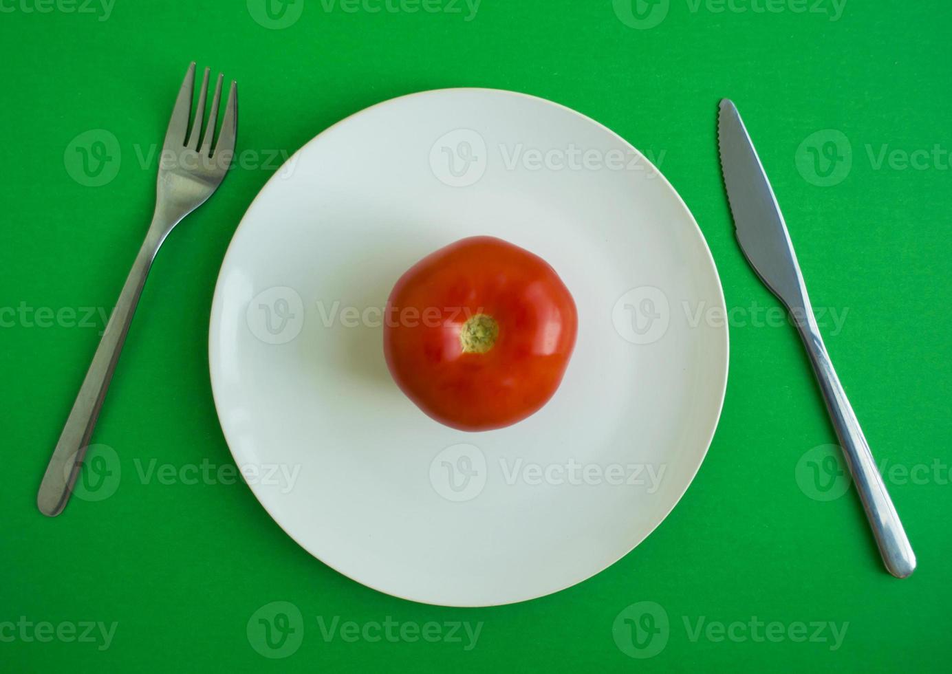 tomat i en tallrik, gaffel och kniv foto