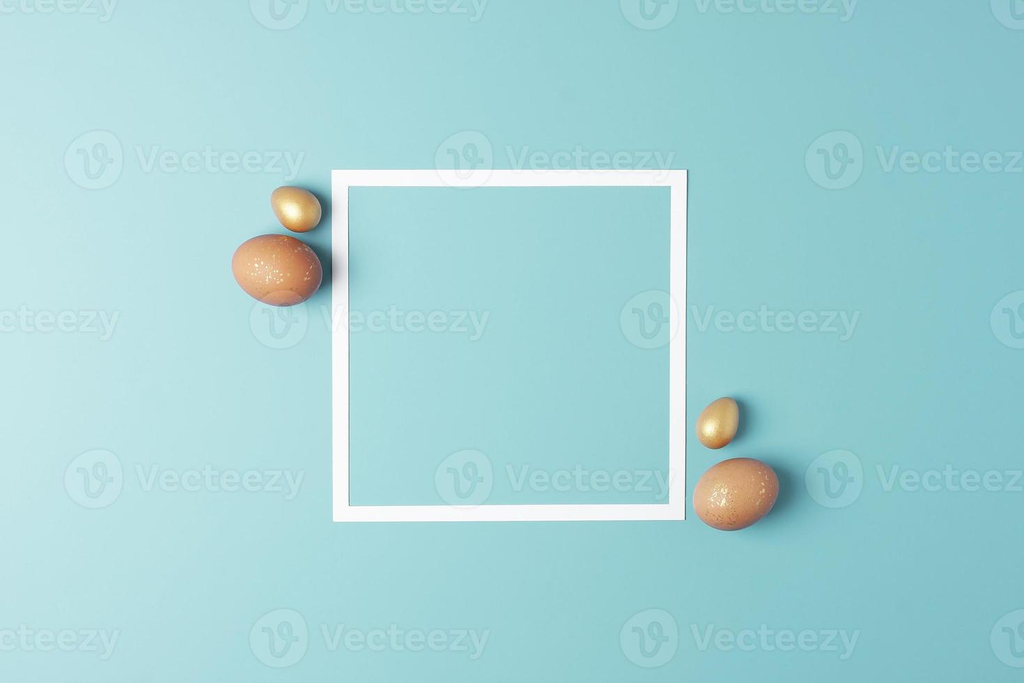 påsk beige och gyllene ägg på blå bakgrund med vit ram. platt lägga, kopia Plats. foto