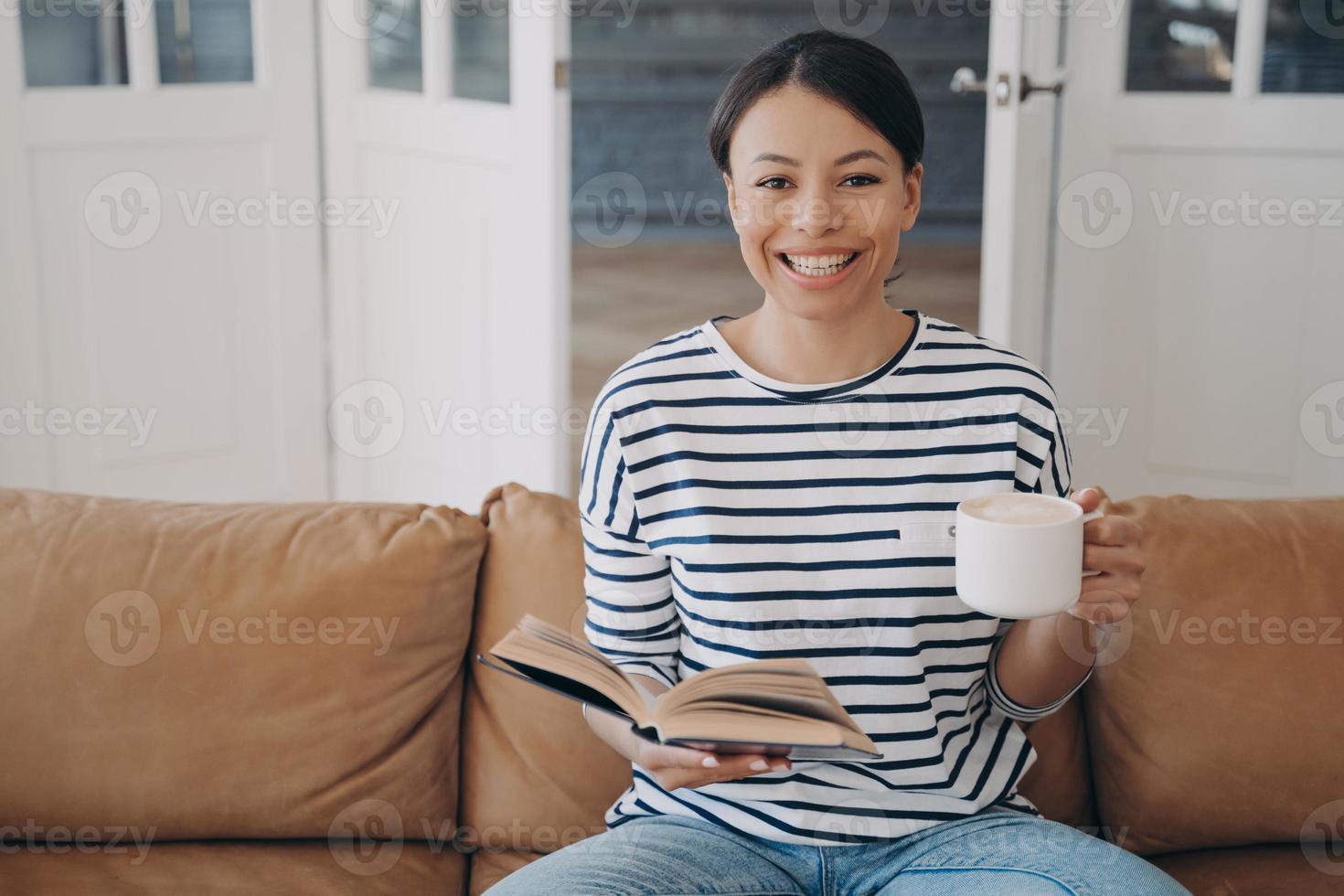 leende ung latinamerikan kvinna är läsning bok. litteratur, inhemsk utbildning på karantän. foto