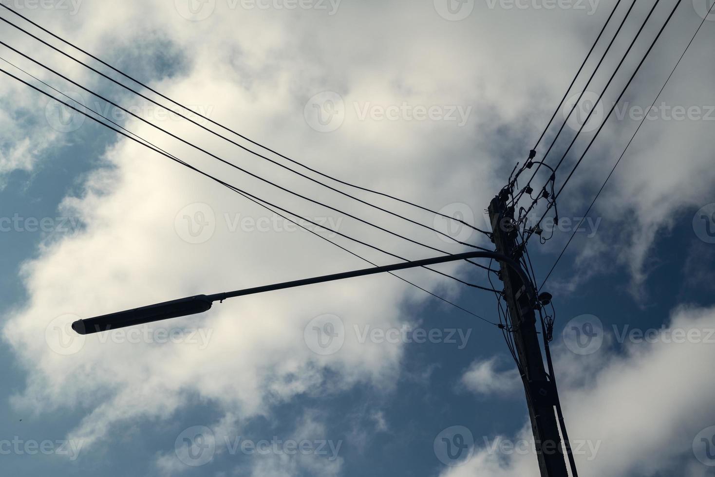 modern elektricitet Pol med lykta och kraft linje kablar. blå himmel och moln som bakgrund. begrepp av modern teknik kunskap för kraft överföring, förbindelse, kommunikation, och belysning foto