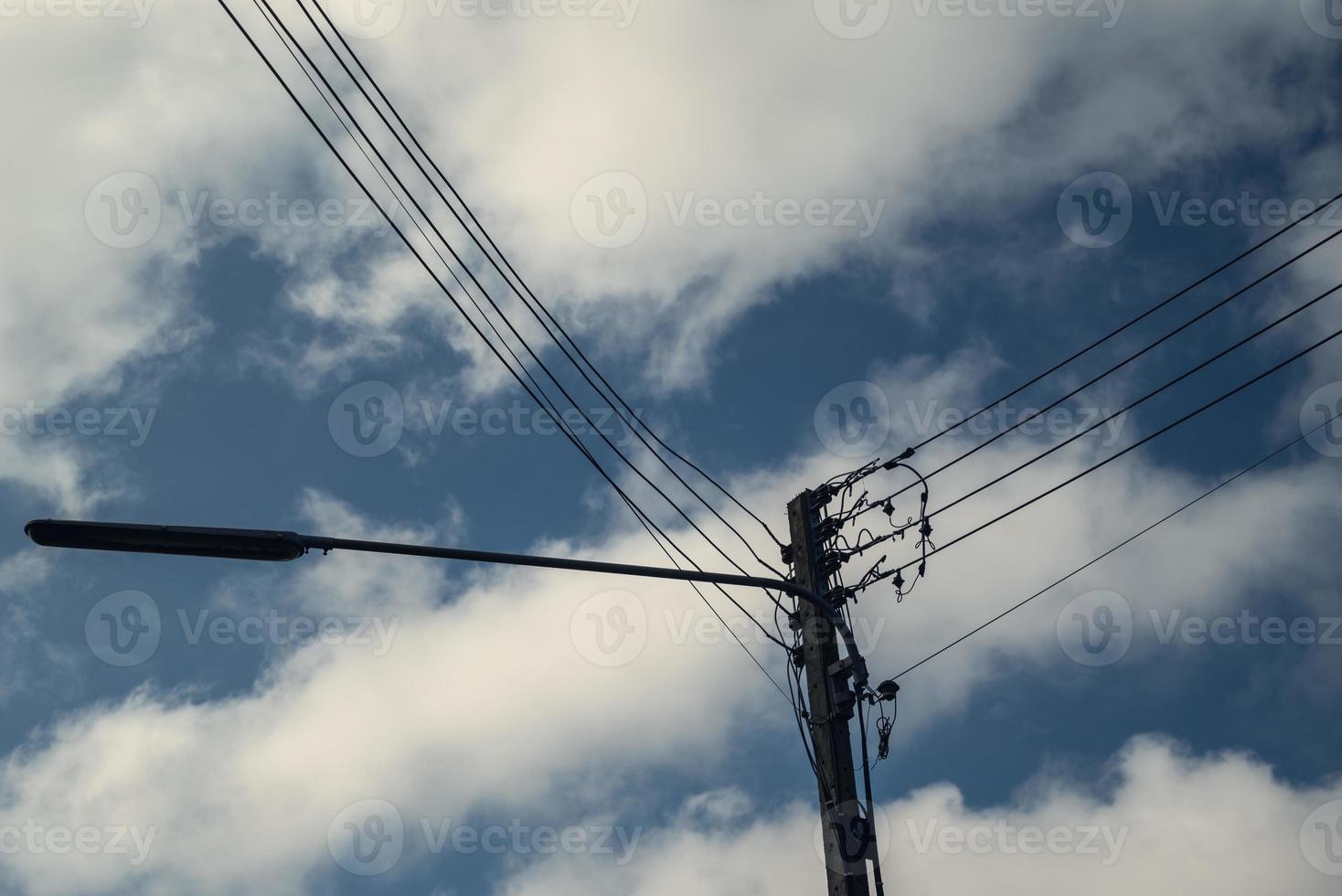 modern elektricitet Pol med lykta och kraft linje kablar. blå himmel och moln som bakgrund. begrepp av modern teknik kunskap för kraft överföring, förbindelse, kommunikation, och belysning foto
