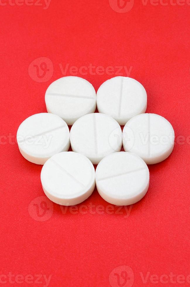 en få vit tabletter lögn på en ljus röd bakgrund yta. bakgrund bild på medicinsk och farmaceutisk ämnen foto