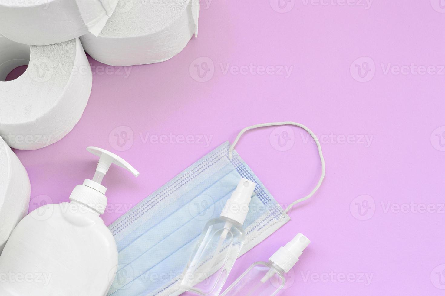 uppsättning av Viktig objekt för covid-19 karantän gånger. toalett papper med kirurgisk ansikte mask och hand desinfektionsmedel med flytande tvål flaska på lila bakgrund foto