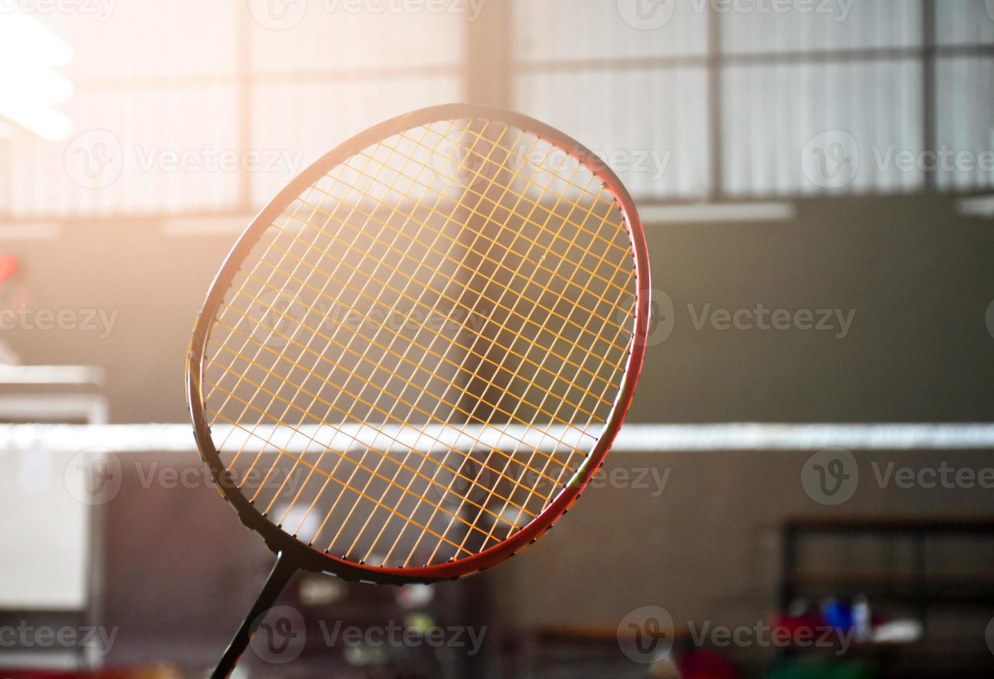 närbild badminton racket i främre av de netto innan tjänande den till annan sida av de domstol, mjuk och selektiv fokus. foto