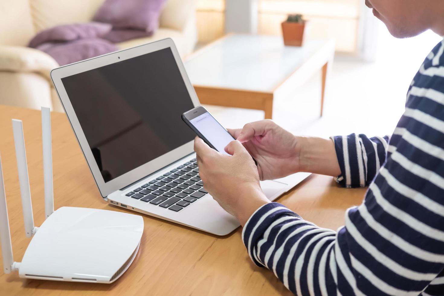 selektiv fokus på män hand innehav smartphone enhet medan sökande för information, webb bläddring i främre av hög hastighet internet router. kommunikation teknologi för digital livsstil. foto