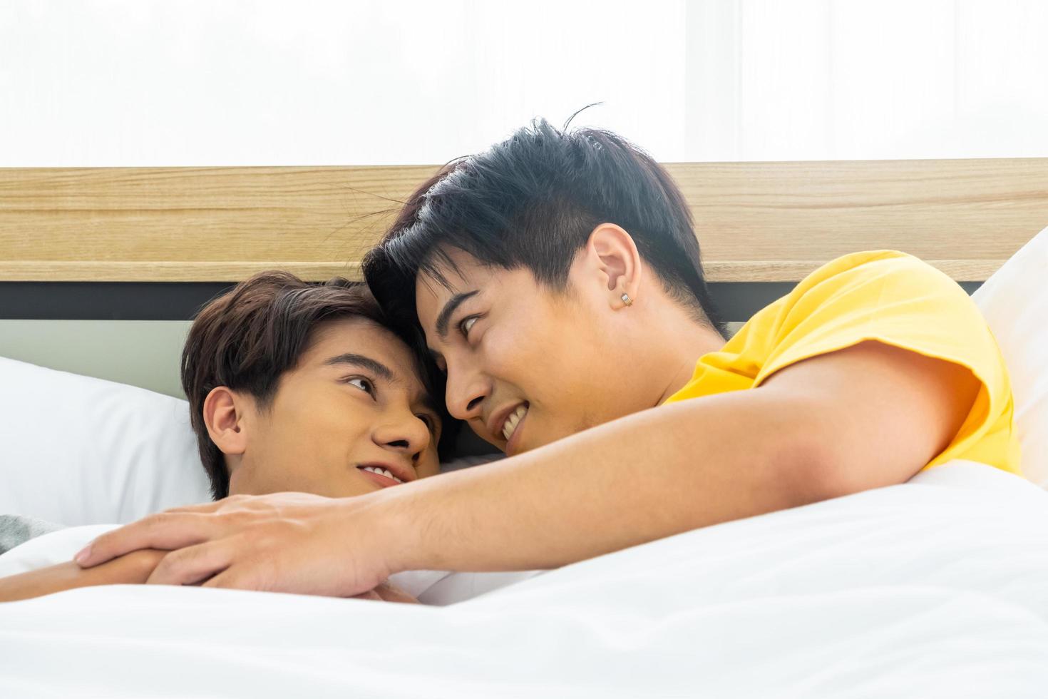 porträtt av ung Gay homosexuell par liggande ner tillsammans på de säng. lycka ögonblick av bisexuell. kön jämlikhet och mänsklig rätt begrepp. foto