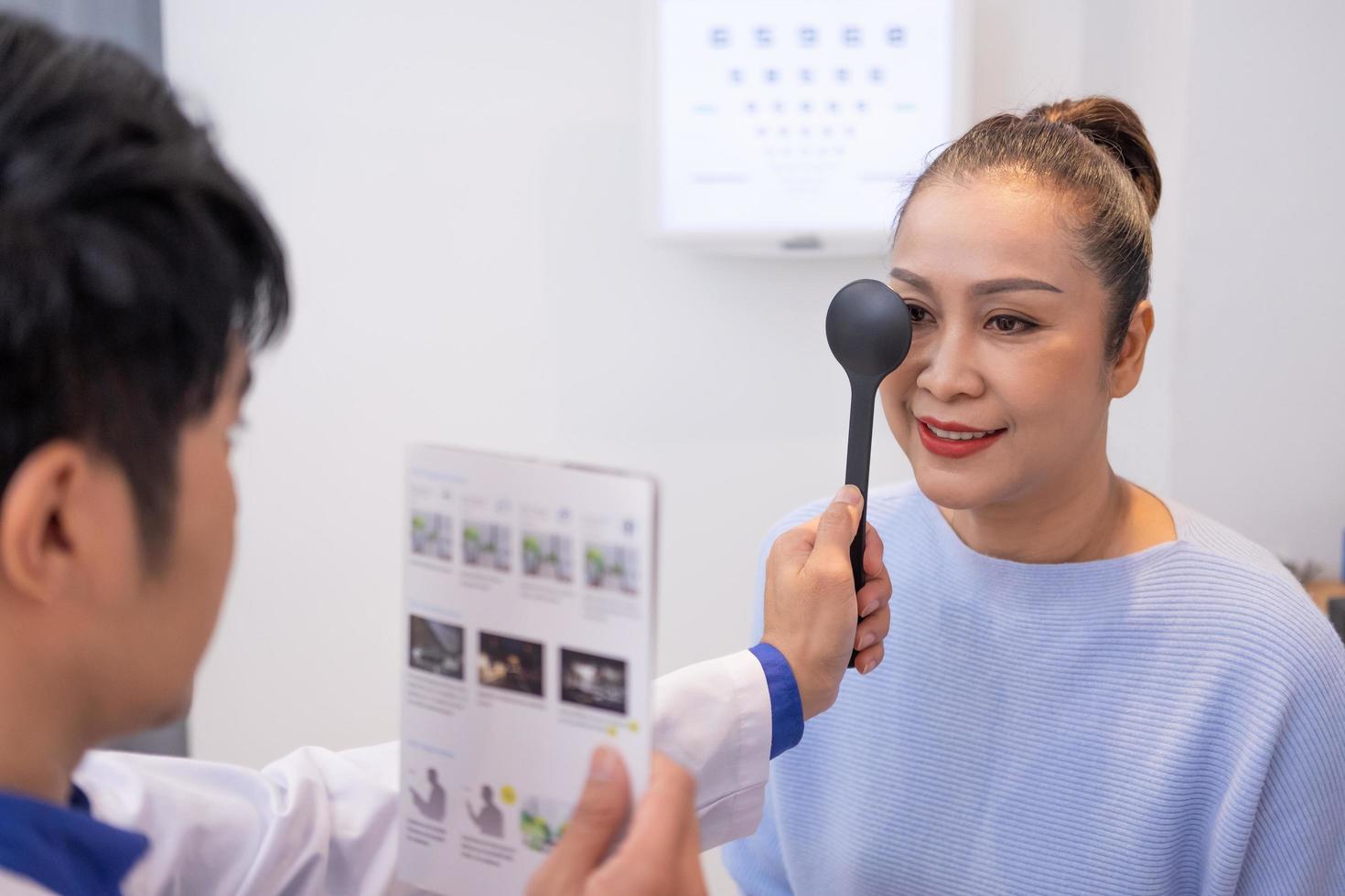 selektiv fokus på kvinnor ansikte. medan läkare använder sig av optometri Utrustning och rättegång glasögon ram till undersöka öga visuell systemet av äldre patient kvinnor med professionell maskin och teknik. foto