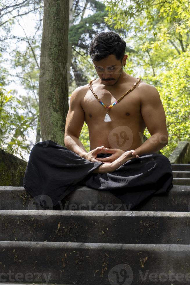 ung man håller på med meditation på en trappa i en skog, mexico foto