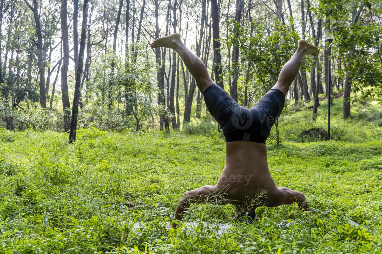 latin amerikan man håller på med yoga hållning, yoga hållning, bi bakåt prsthatah brahmara, skog foto