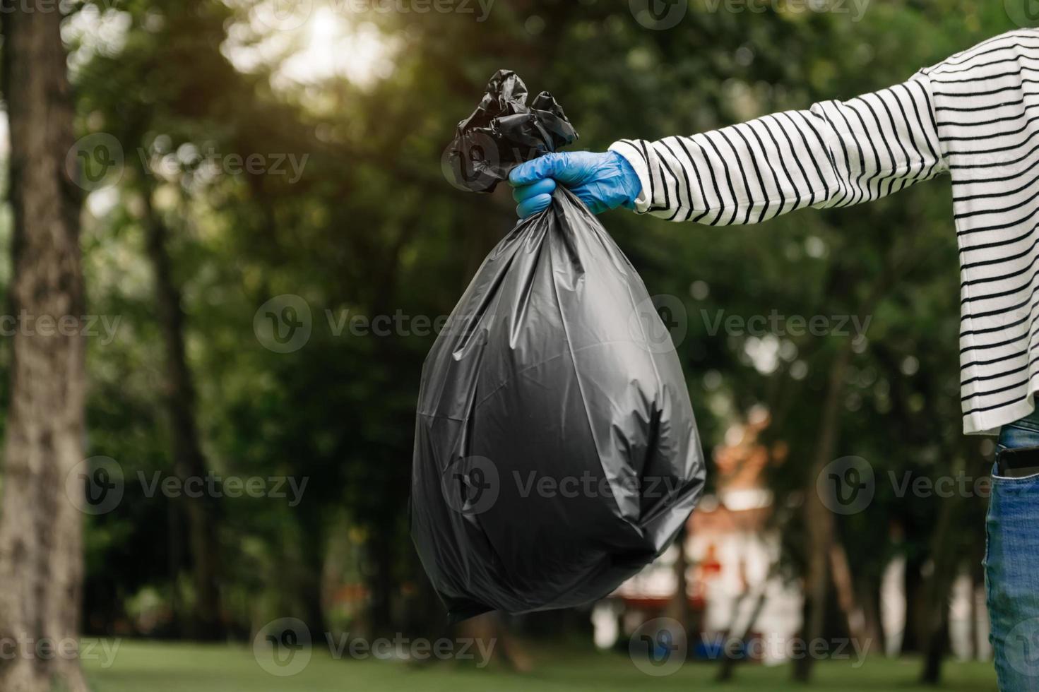 hand innehav sopor svart väska sätta i till skräp till rena. clearing, förorening, ekologi och plast begrepp. på parkera foto