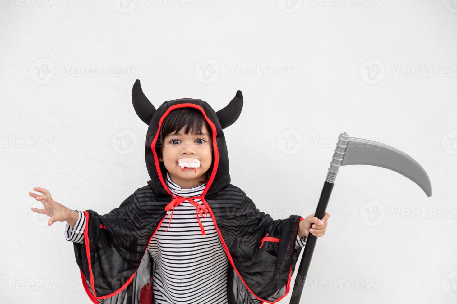 barn flicka bär mystisk halloween klänning innehav en skära på vit bakgrund foto