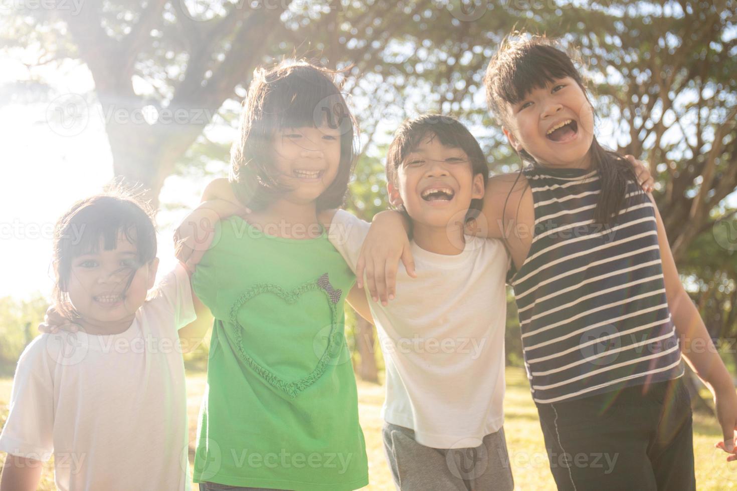 grupp av dagis barn vänner ärm runt om och leende roligt med solnedgång foto