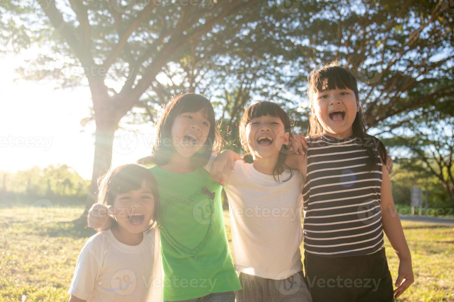 grupp av dagis barn vänner ärm runt om och leende roligt med solnedgång foto