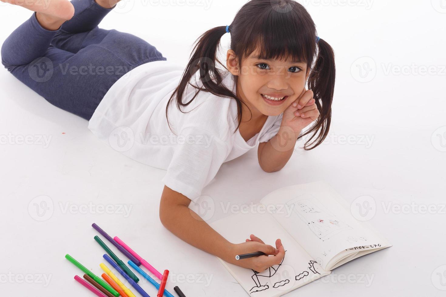 söt liten flicka håller på med läxa, läsning en bok, färg sidor, skrivning och målning. barn måla. barn dra. preschooler med böcker på Hem. foto