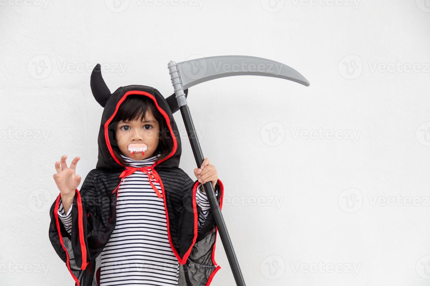 barn flicka bär mystisk halloween klänning innehav en skära på vit bakgrund foto