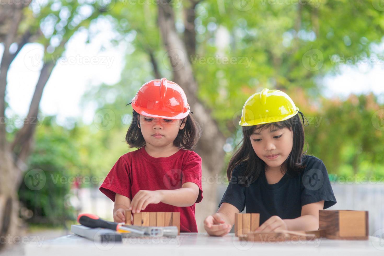 asiatisk syskon flickor bär teknik hattar byggnad hus från de trä- leksak. till inlärning och förbättra utveckling, liten arkitekt. foto