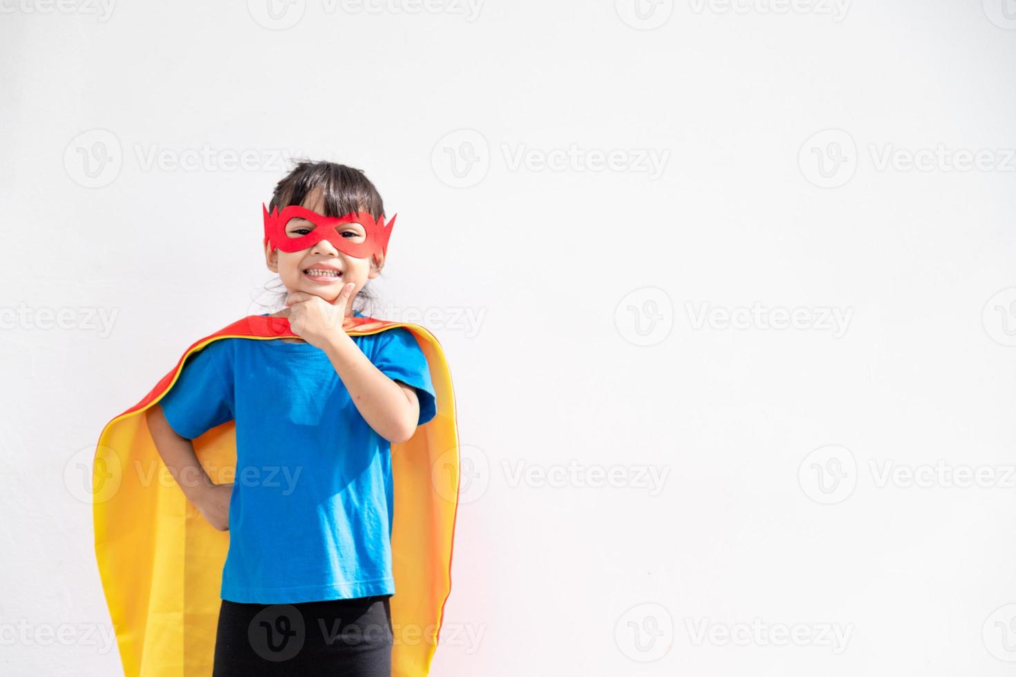 liten barn flicka spelar superhjälte. barn på de vit bakgrund. flicka kraft begrepp foto