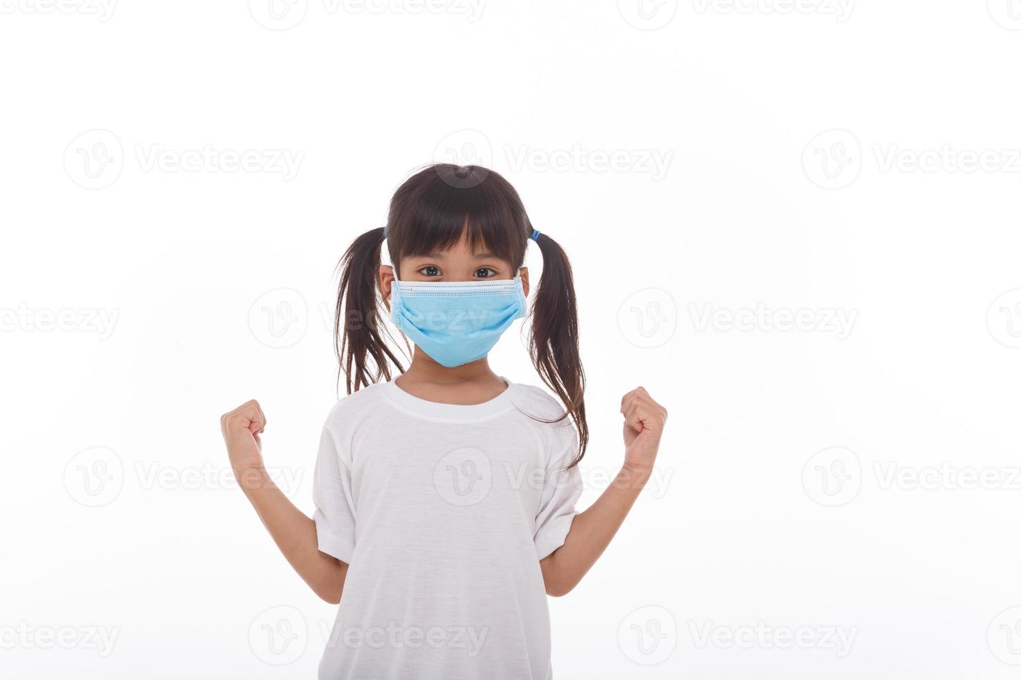 Asien flicka bär mask till skydda mot coronavirus, flicka visa en näve uppmuntra till bekämpa smittosam sjukdom begrepp sluta virus covid 19 utbrott till vinna på vit bakgrund foto