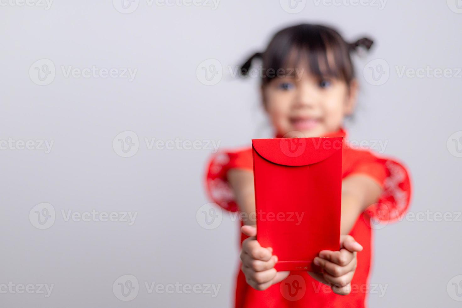 Lycklig liten asiatisk flicka i kinesisk traditionell klänning leende och innehav en röd kuvert. Lycklig kinesisk ny år begrepp. foto
