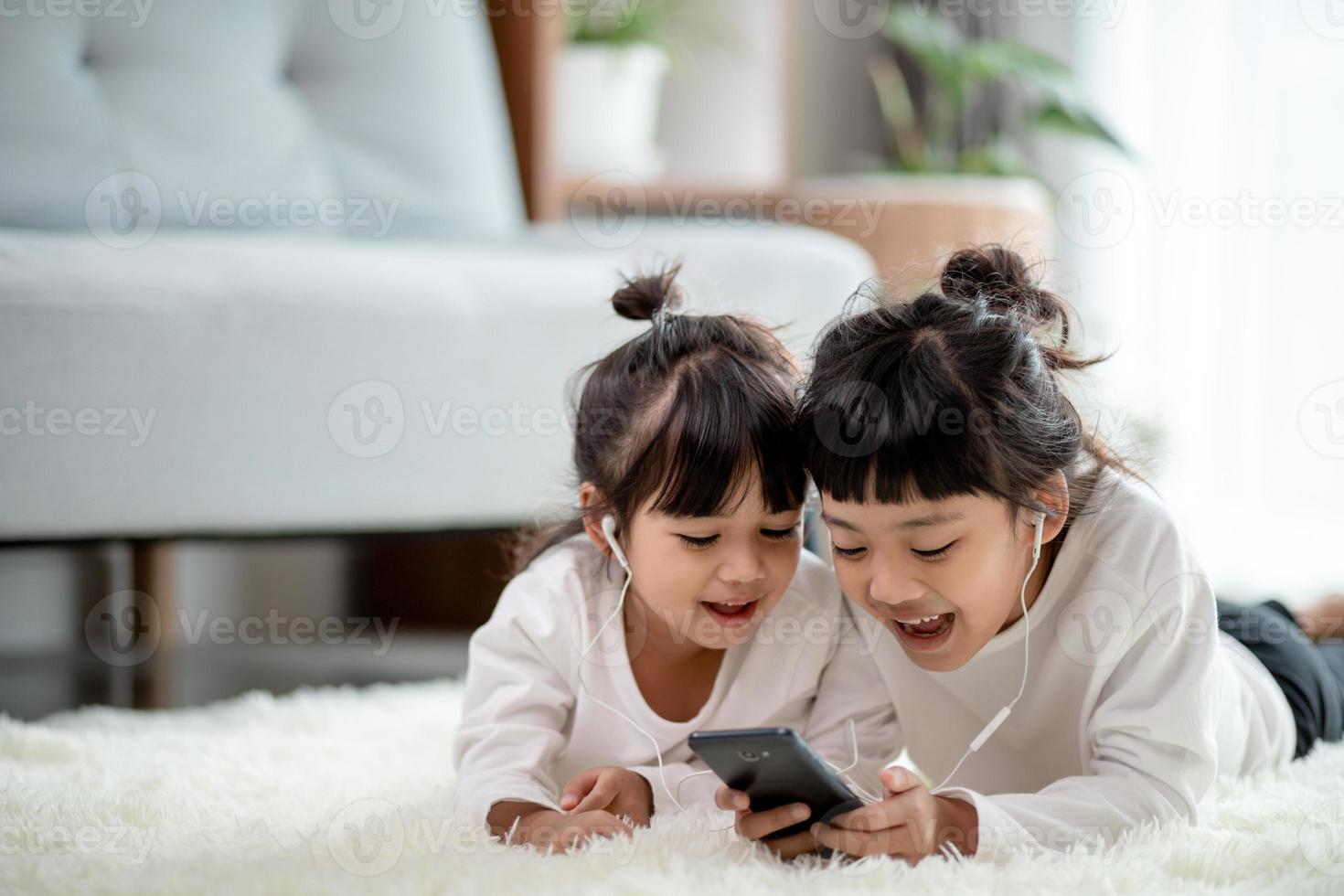 asiatisk syskon tillsammans på de golv använder sig av smartphone foto