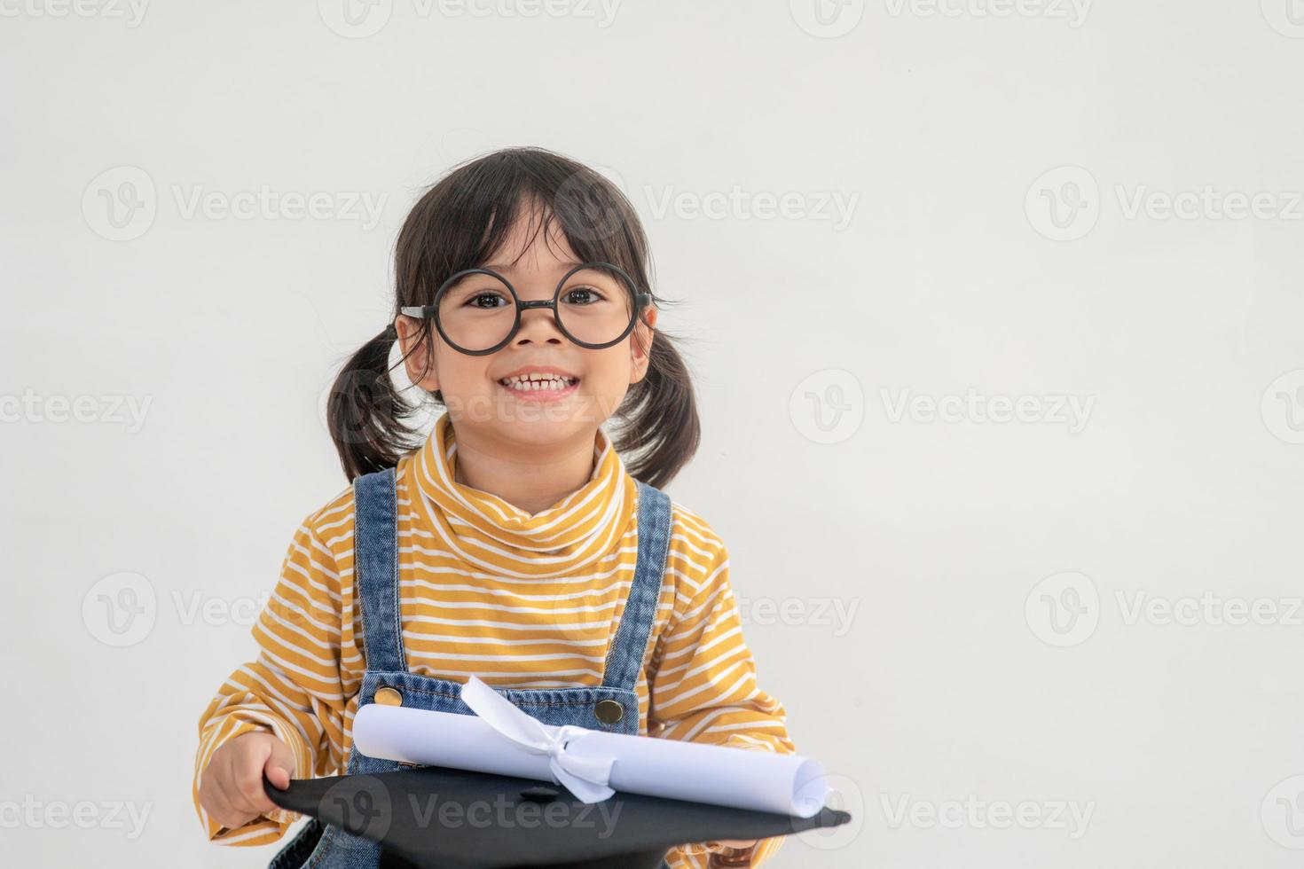 barn flicka bär en examen keps över vit bakgrund mycket Lycklig och upphetsad håller på med vinnare gest med vapen Uppfostrad, leende och skrikande för Framgång. firande begrepp. foto