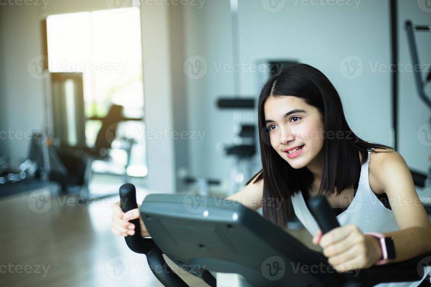 passa ung flicka använder sig av övning cykel på de Gym. kondition kvinna använder sig av luft cykel på Gym. foto