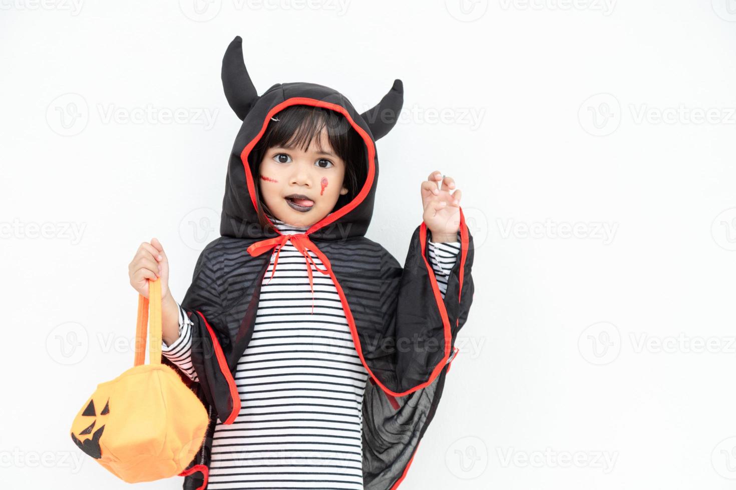 rolig halloween unge begrepp, liten söt flicka med kostym halloween spöke skrämmande han innehav orange pumpa spöke på hand, på vit bakgrund foto