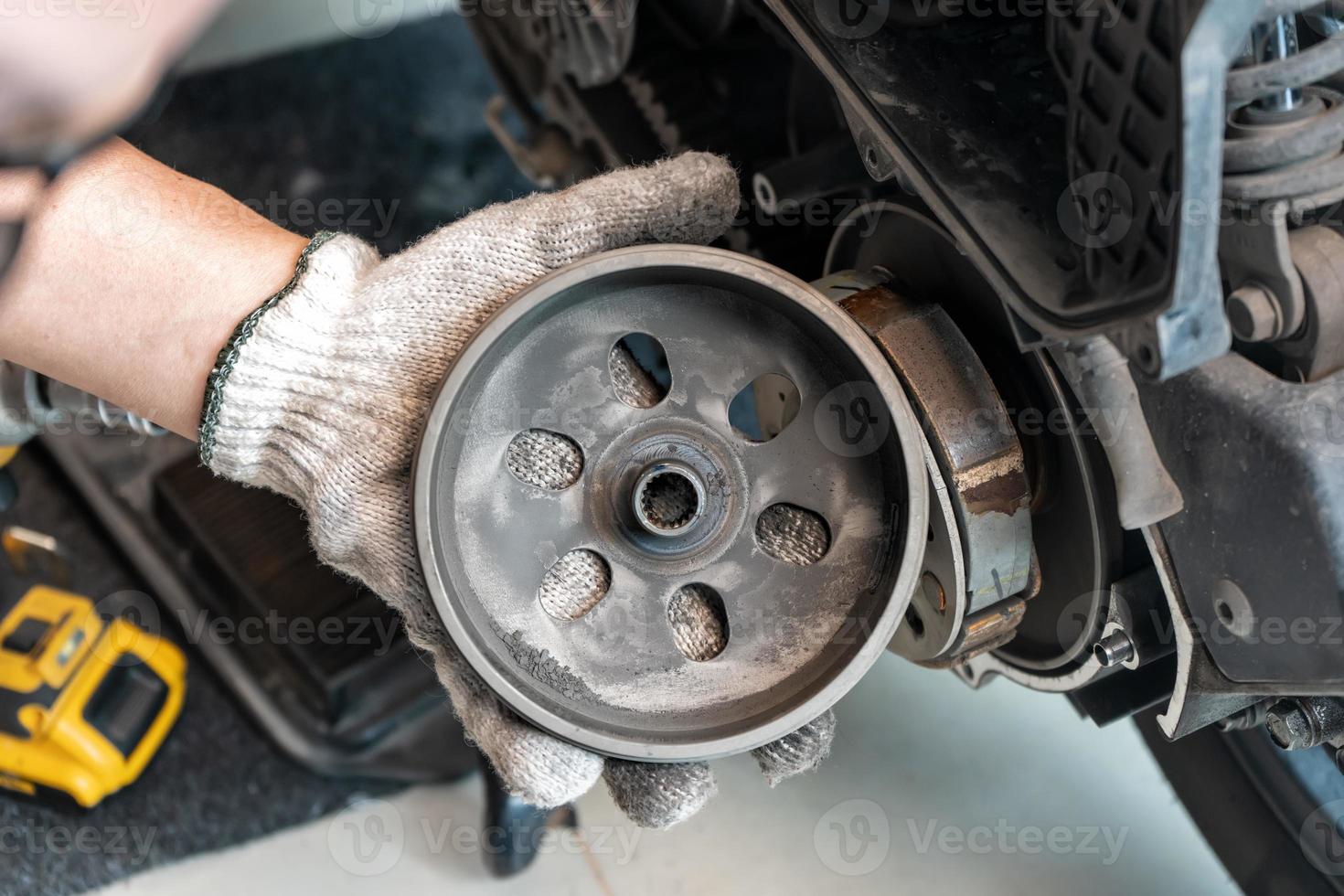 mekaniker kolla upp bil överföring systemet eller bak- koppling remskiva av skoter motorcyklar i garage. underhåll, reparera motorcykel begrepp i garage .selektiv fokus foto