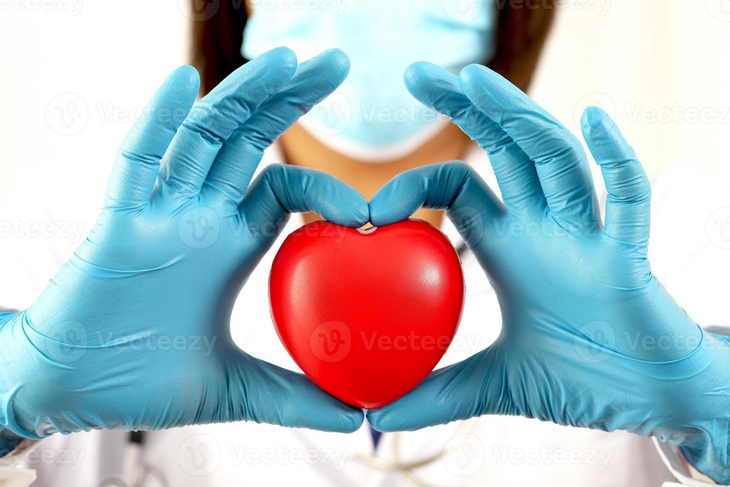 ung kvinna läkare innehav en röd hjärta stående på en vit bakgrund foto