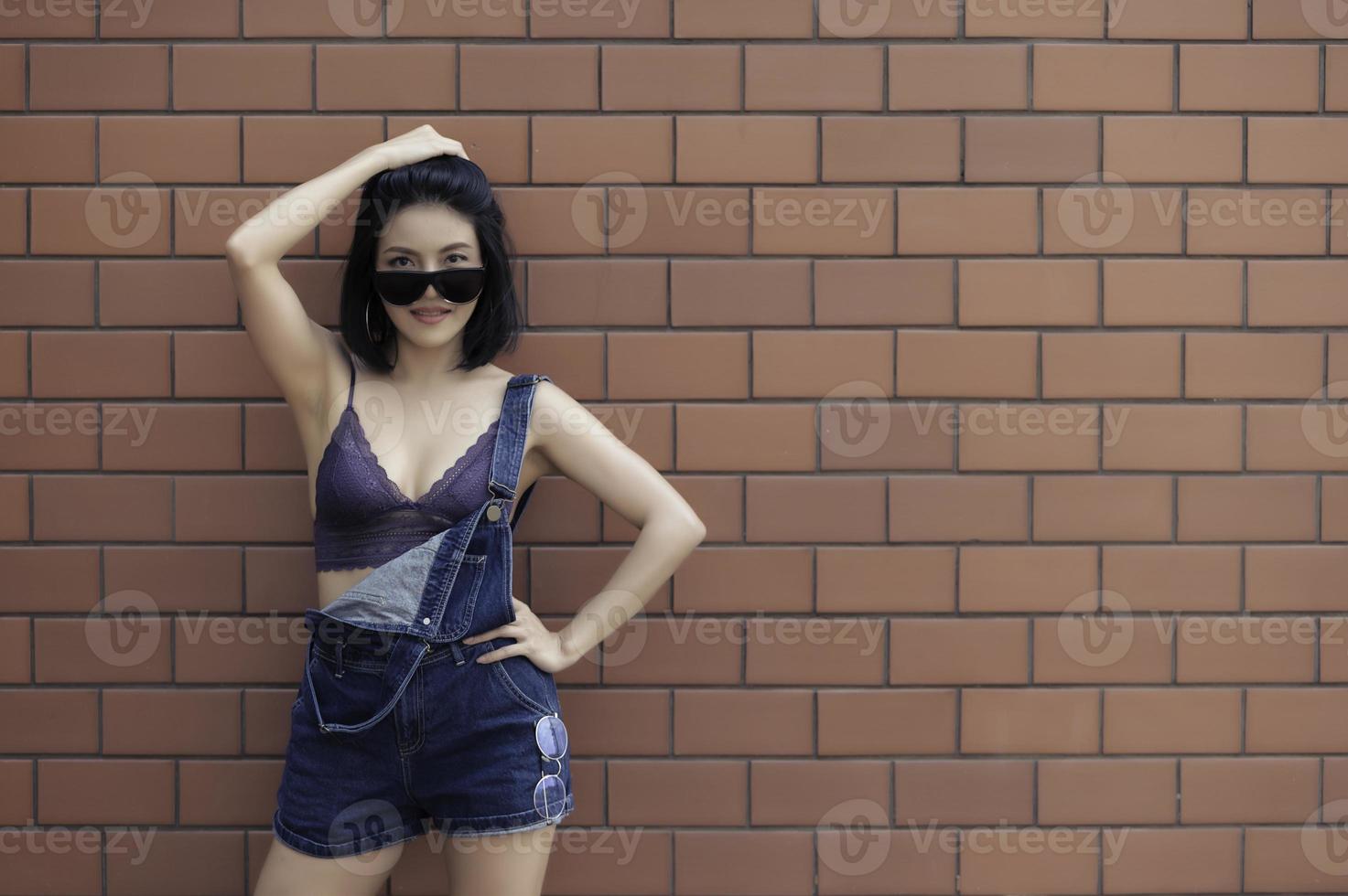 porträtt av hipster flicka på tegel vägg bakgrund, vacker asiatisk kvinna utgör för ta en Foto