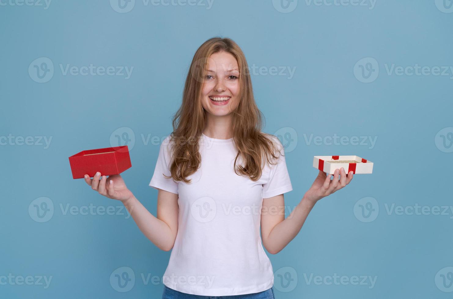 romantisk gåva. Lycklig ung kvinna öppnas hjärtans dag gåva på blå studio foto