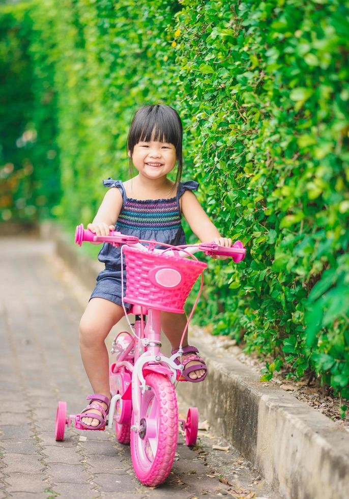 flicka som cyklar på en rosa cykel foto