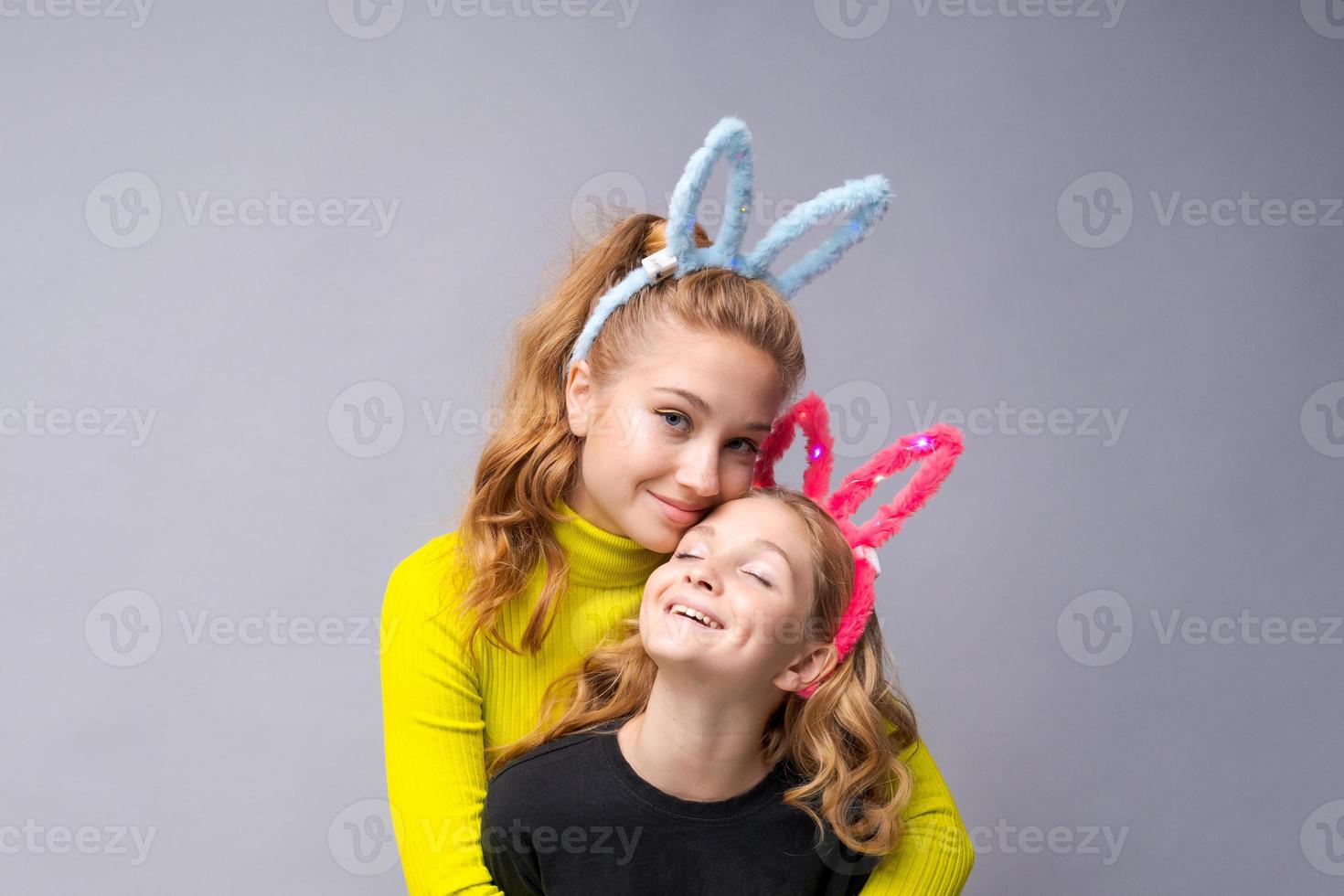 närbild porträtt två glad Söt ung flickor med kanin öron i gul foto
