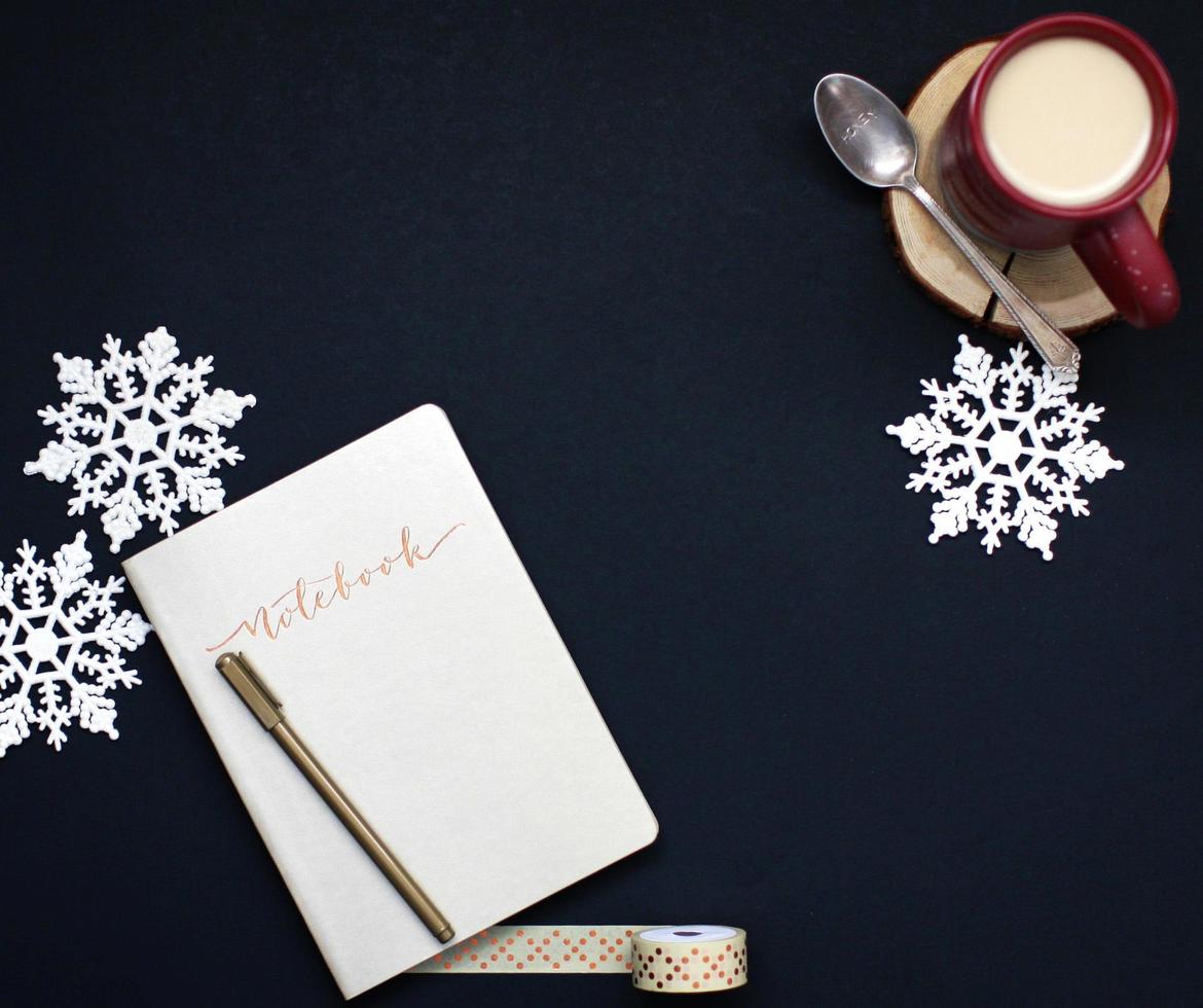 kaffe och anteckningsbok med snöflingor på en mörk bakgrund foto