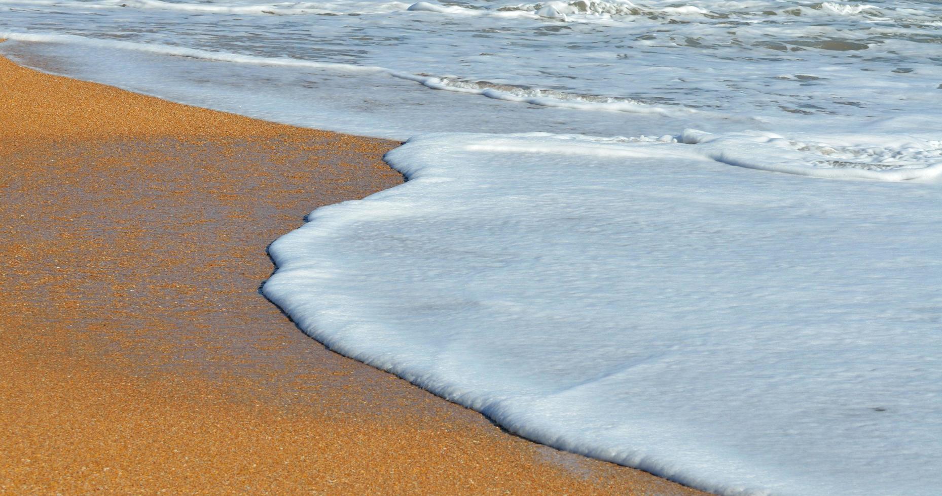 vitt skum på stranden foto