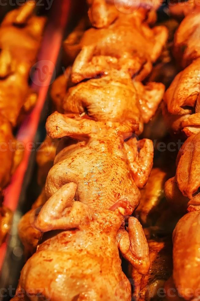 saftig och smakrik grillad kyckling med en gyllene skorpa på en grillspett i en rad. foto