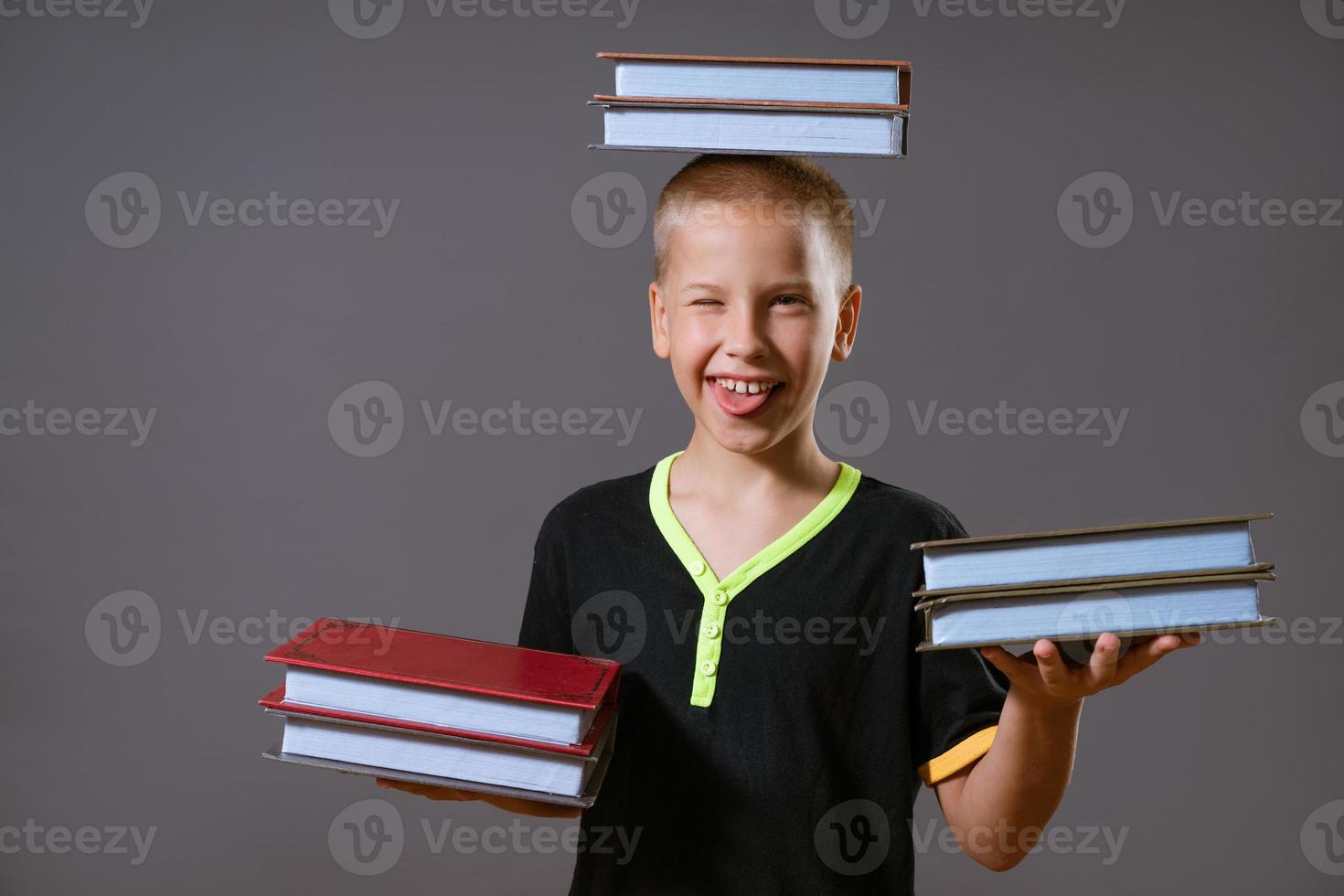 liten pojke håll de stackar av böcker i din händer och på din huvud foto