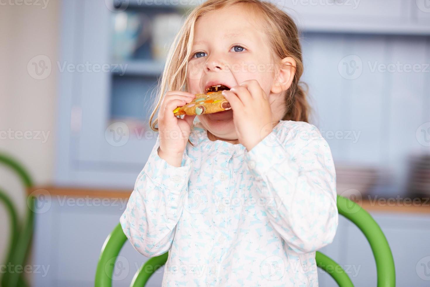 ung flicka sitter vid bordet äter kakan foto