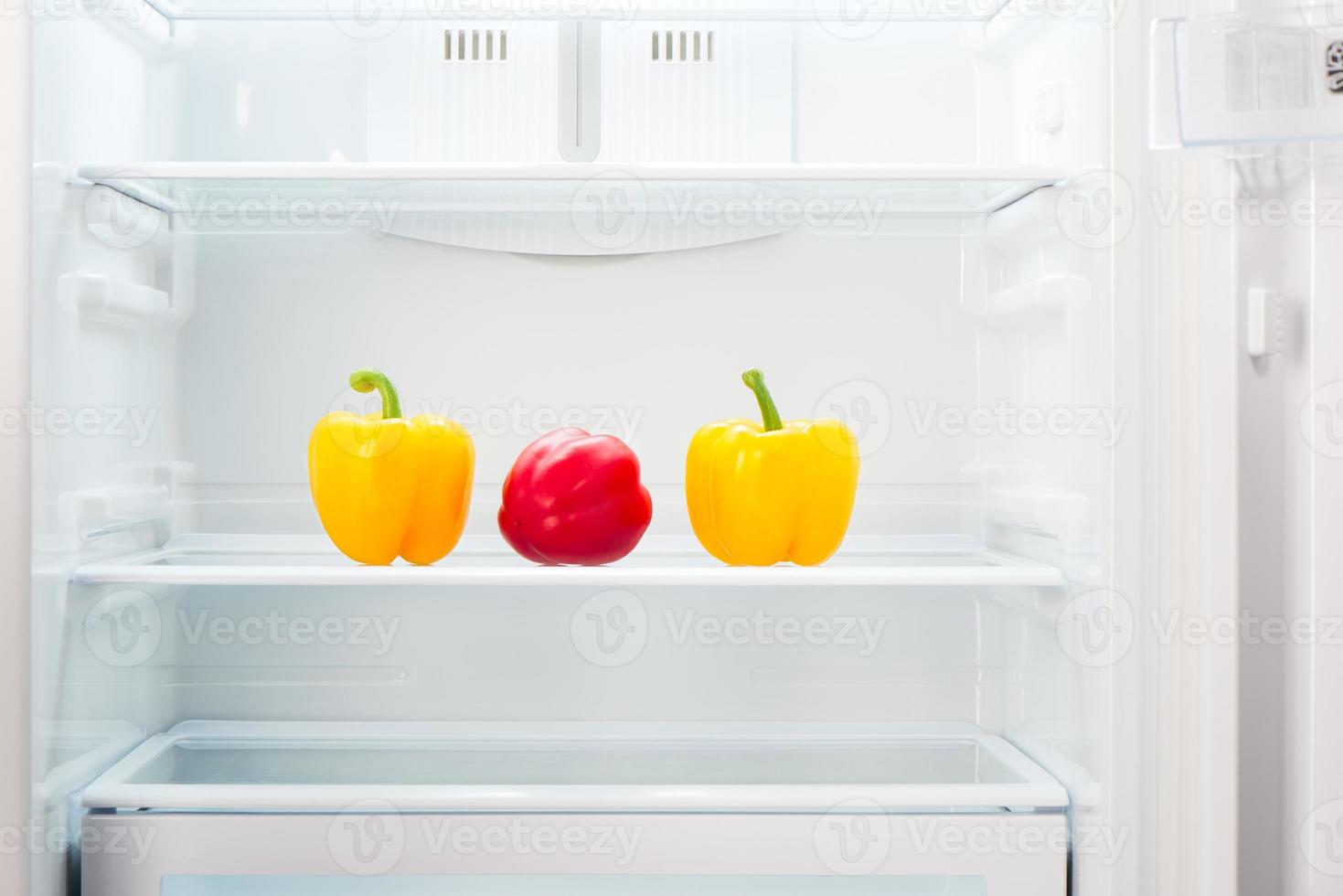 två gula med en röd paprika i kylskåpshyllan foto