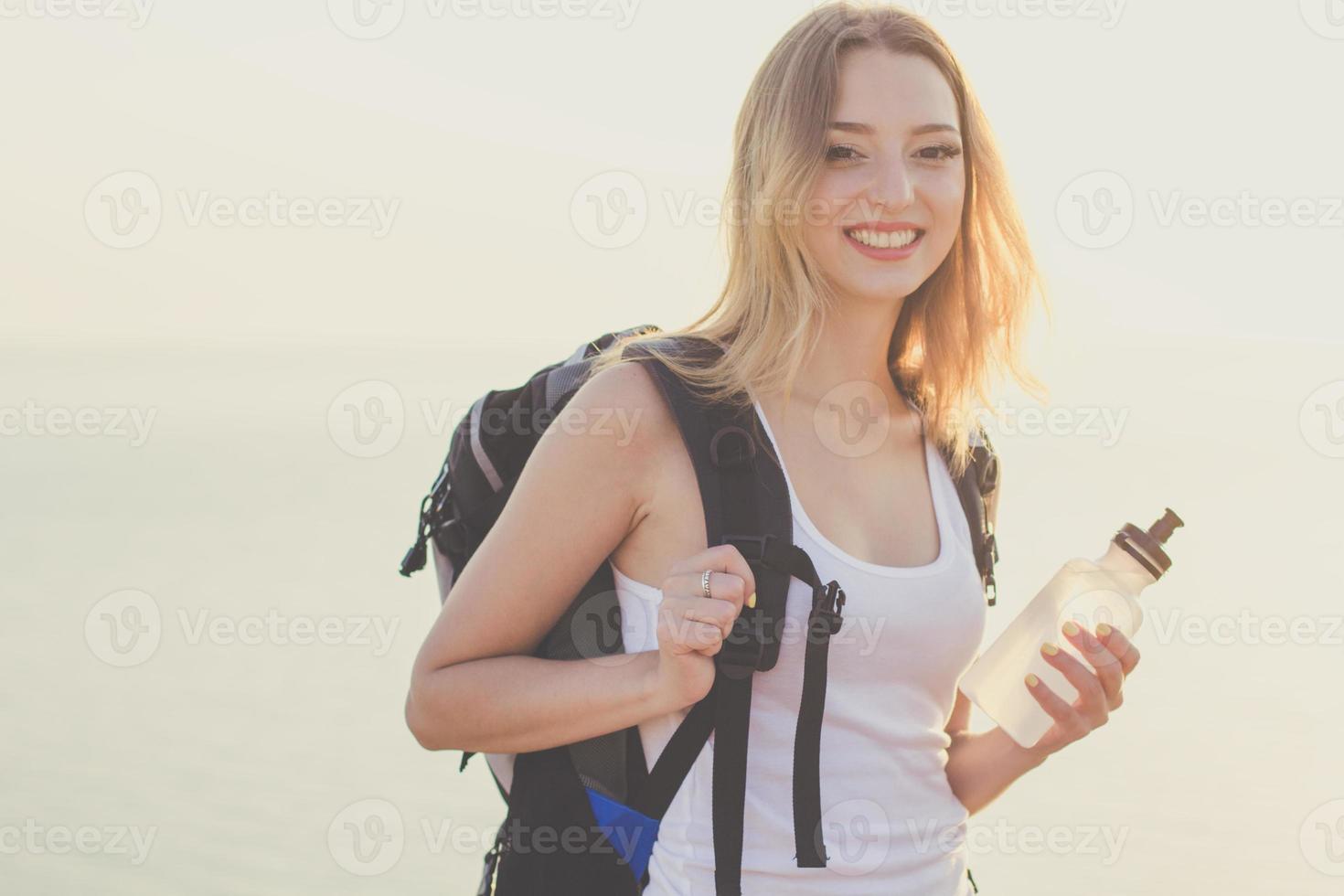 leende backpacker flicka håller flaskan med vatten foto